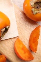 Photo of Delicious ripe persimmons on light wooden table, top view