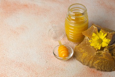 Natural beeswax blocks, dipper and jar of honey on color textured table. Space for text