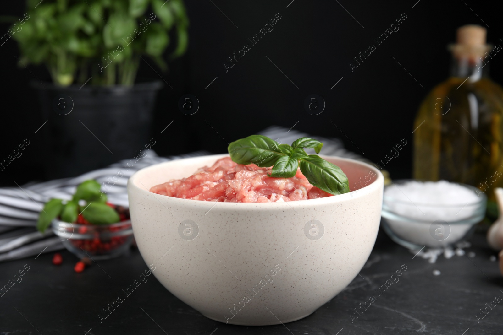 Photo of Raw chicken minced meat with basil on black table, closeup