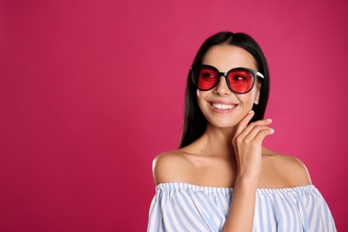 Photo of Beautiful woman wearing sunglasses on pink background. Space for text