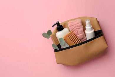 Preparation for spa. Compact toiletry bag with different cosmetic products and eucalyptus on pink background, top view. Space for text