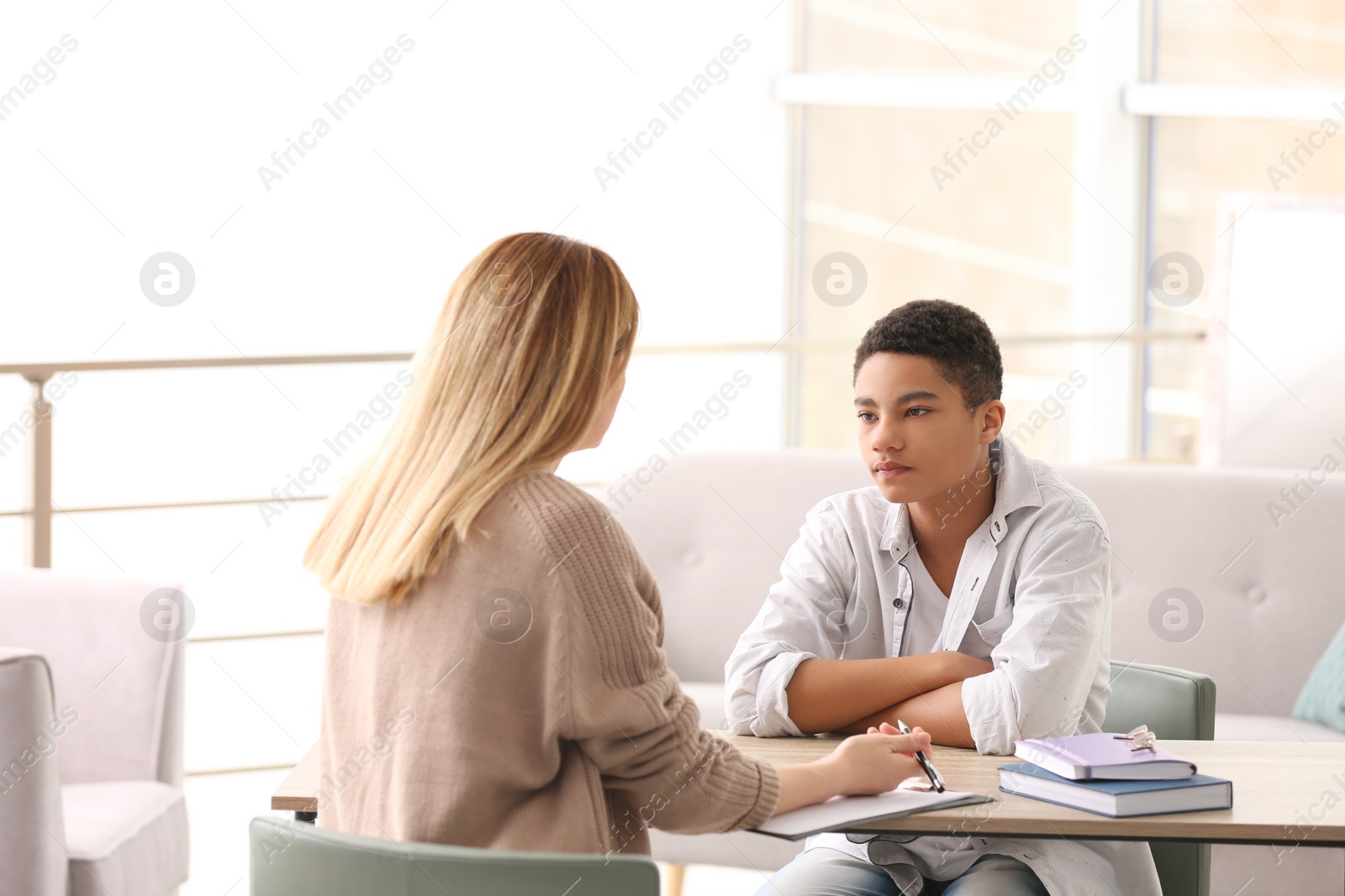 Photo of Young female psychologist working with teenage boy in office