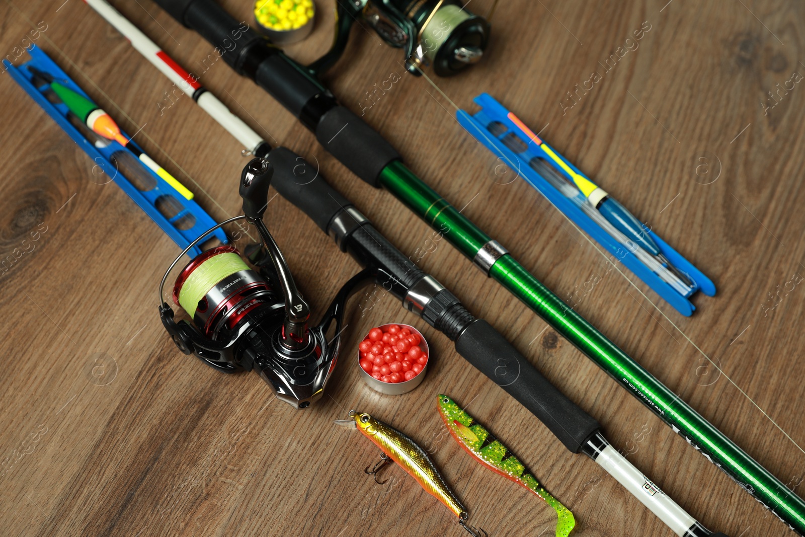 Photo of Spinning rods and fishing tackle on wooden background, above view