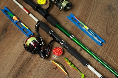 Photo of Spinning rods and fishing tackle on wooden background, above view