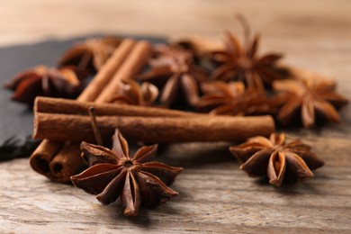 Aromatic cinnamon sticks and anise stars on wooden table, closeup