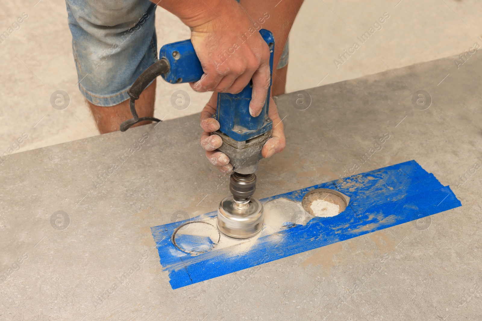 Photo of Worker making socket hole in tile indoors, closeup