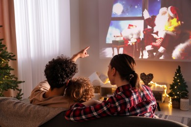 Photo of Family watching Christmas movie via video projector at home, back view