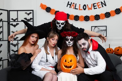 Group of people in scary costumes with carved pumpkin indoors. Halloween celebration