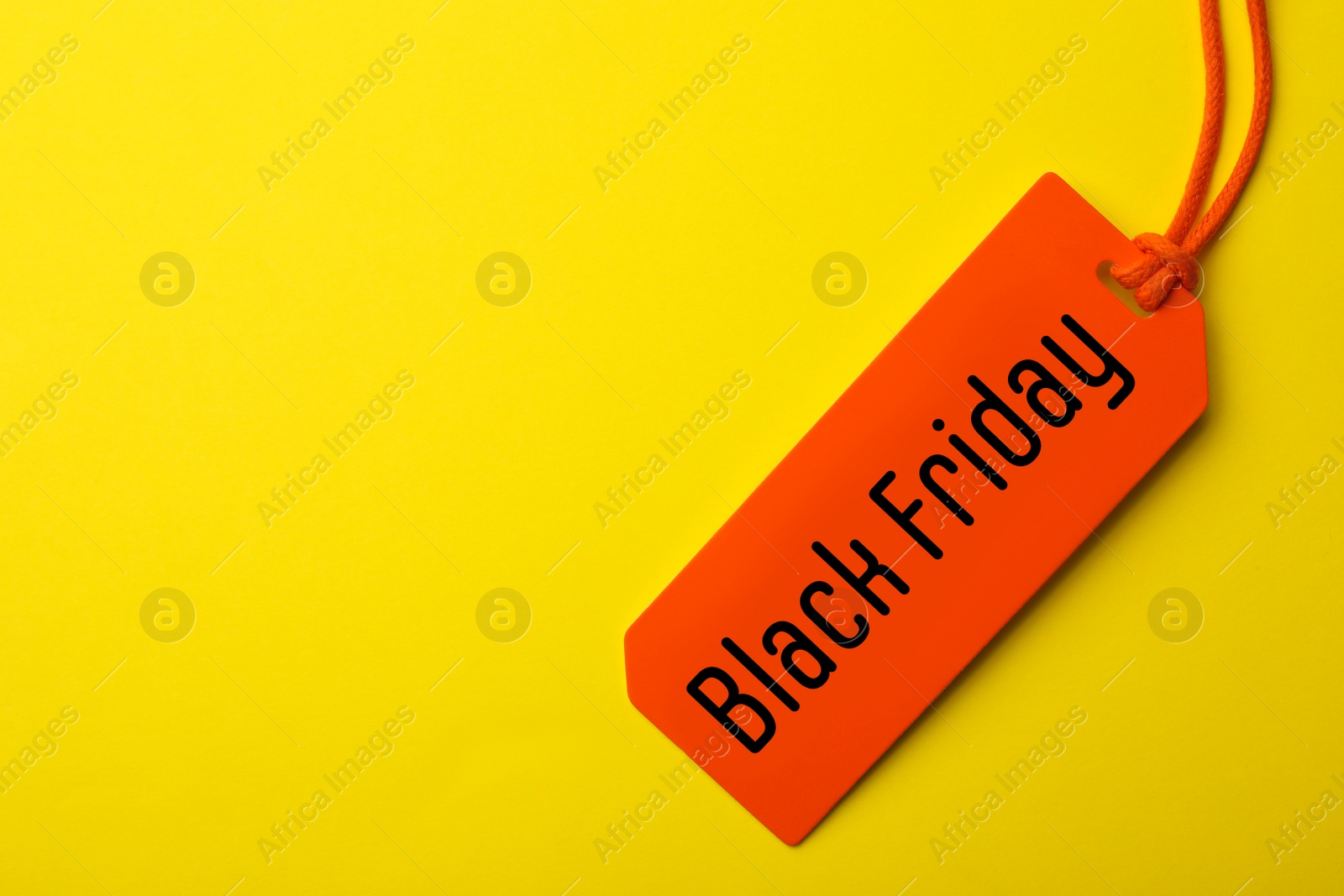 Image of Tag with phrase BLACK FRIDAY on yellow background, top view. Space for text