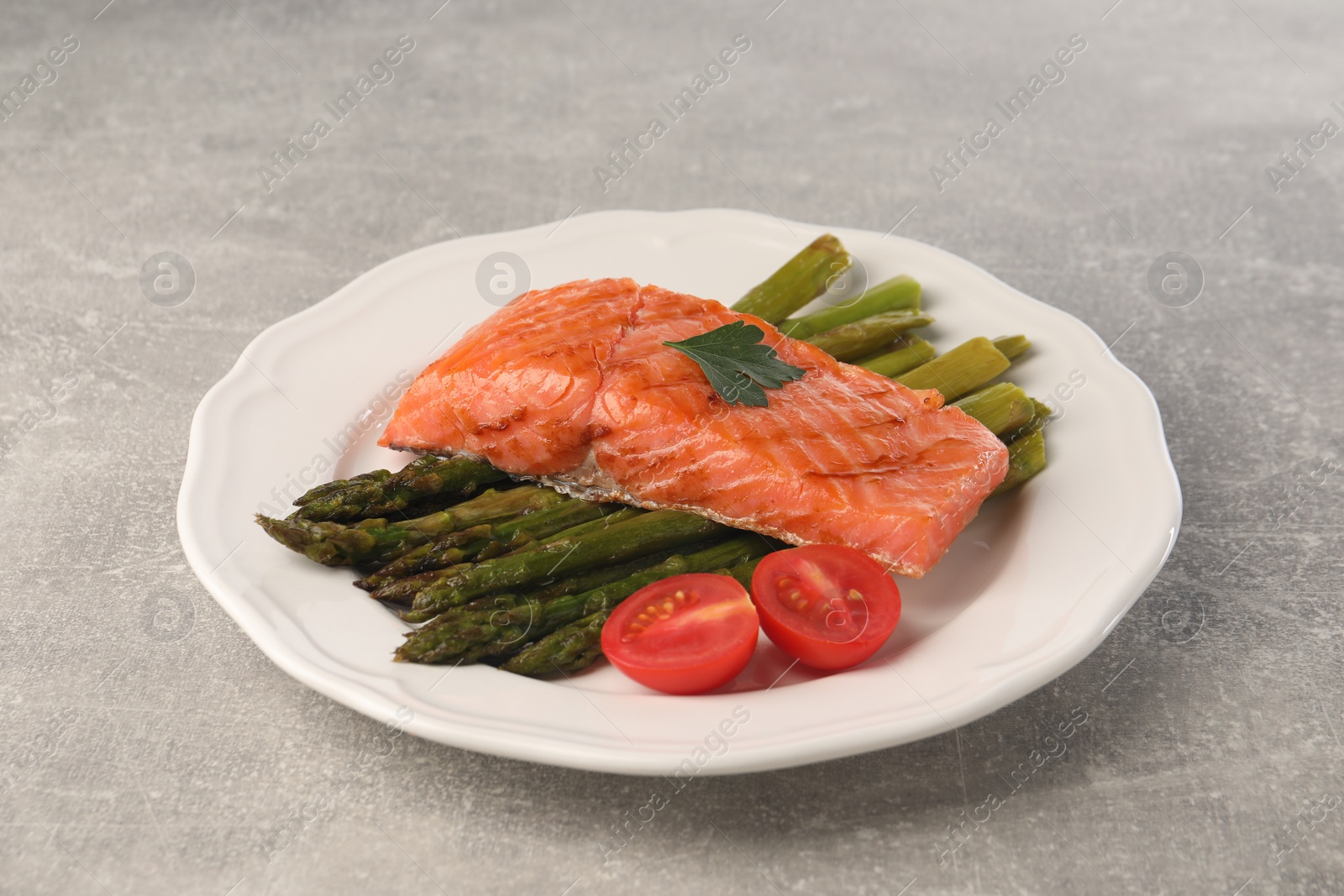 Photo of Tasty grilled salmon with tomatoes and asparagus on grey table