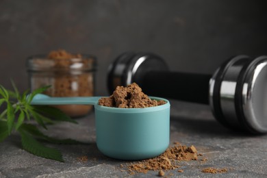 Photo of Hemp protein powder and dumbbell on grey table