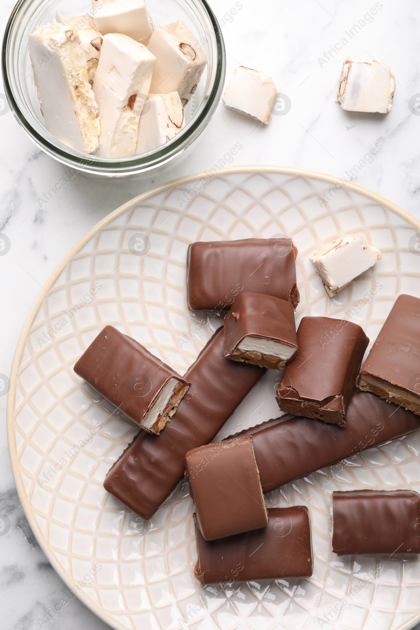 Photo of Tasty chocolate bars and nougat on white table, flat lay