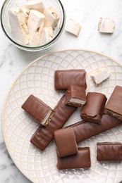 Tasty chocolate bars and nougat on white table, flat lay