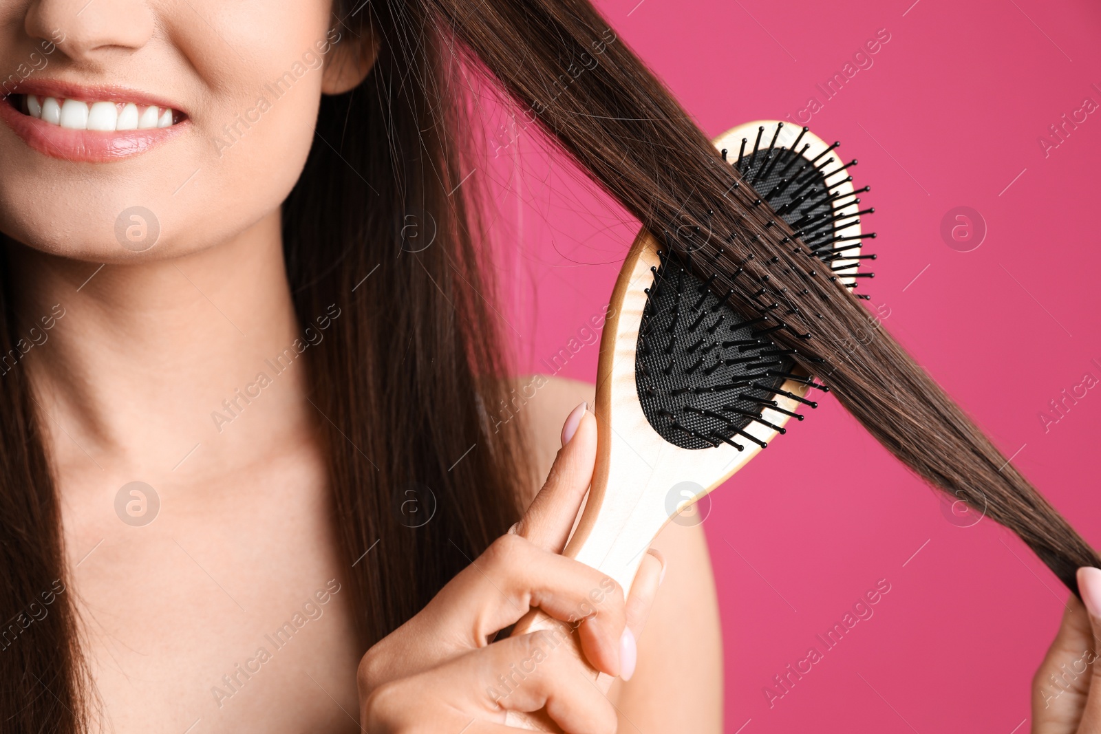 Photo of Woman with hair brush on color background, closeup