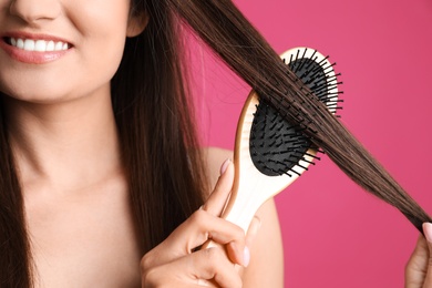 Woman with hair brush on color background, closeup