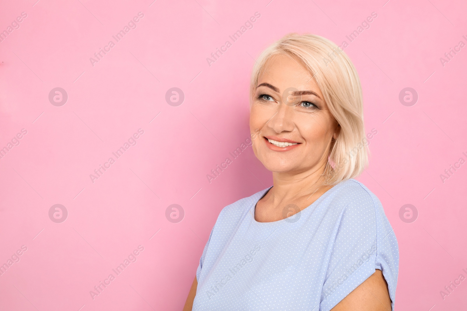 Photo of Portrait of mature woman with beautiful face on pink background. Space for text