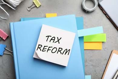 Reminder note with words TAX REFORM and stationery on table, flat lay