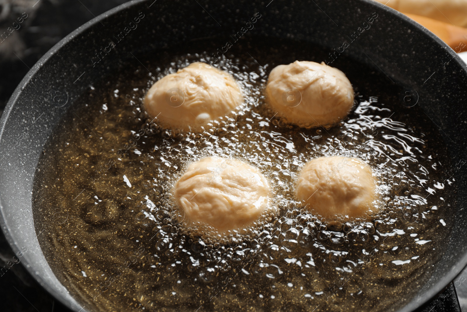 Photo of Cooking delicious donuts in hot oil, closeup