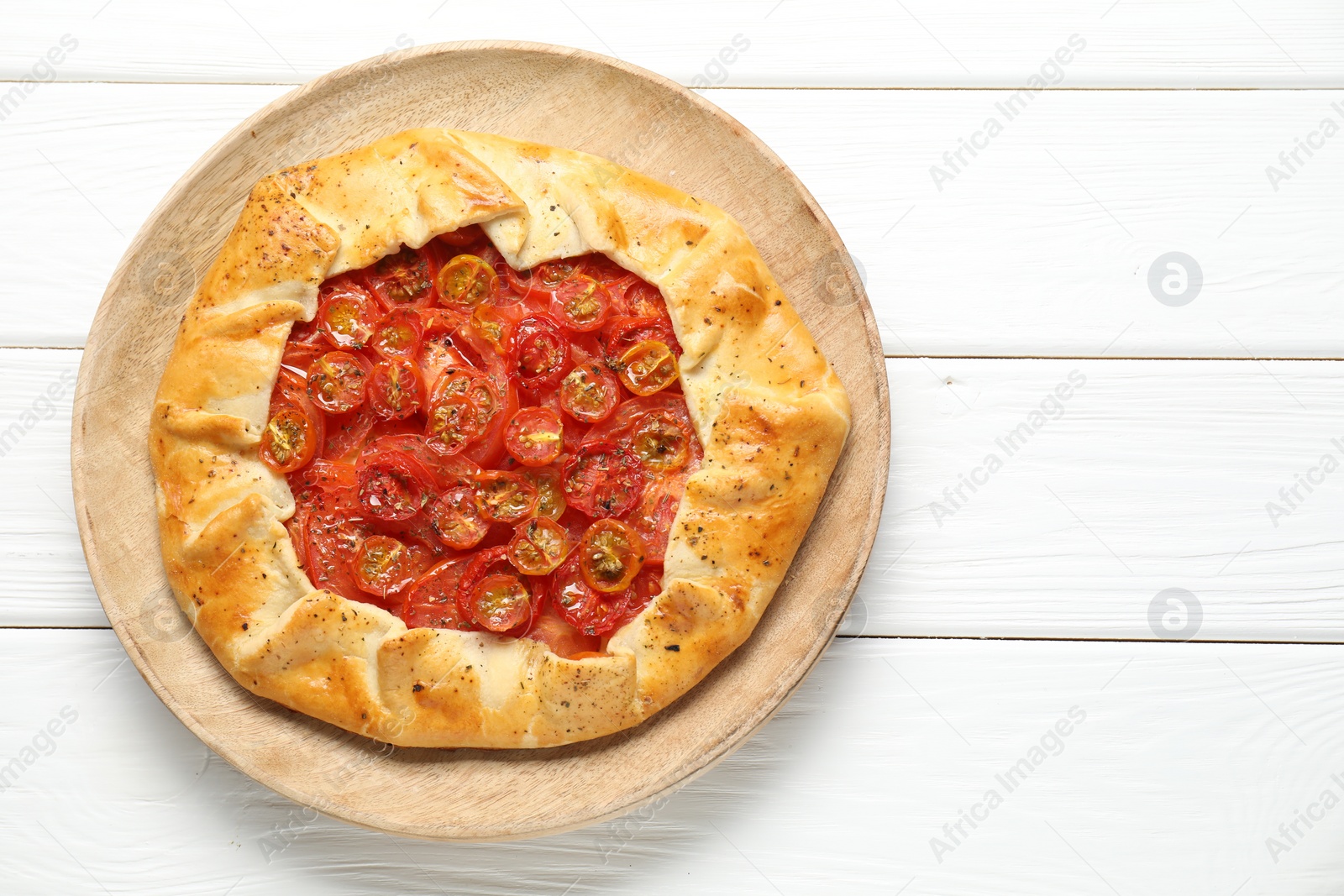 Photo of Tasty tomato galette (Caprese galette) on white wooden table, top view. Space for text