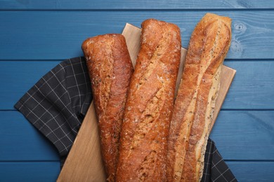 Photo of Tasty buckwheat baguettes on blue wooden table, flat lay