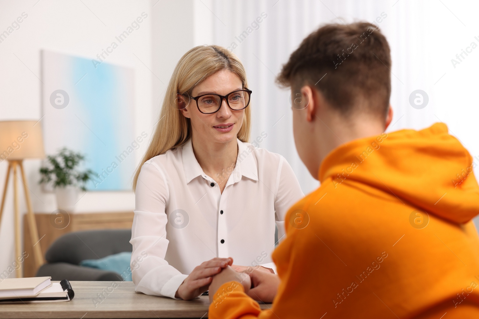 Photo of Psychologist working with teenage boy at table in office