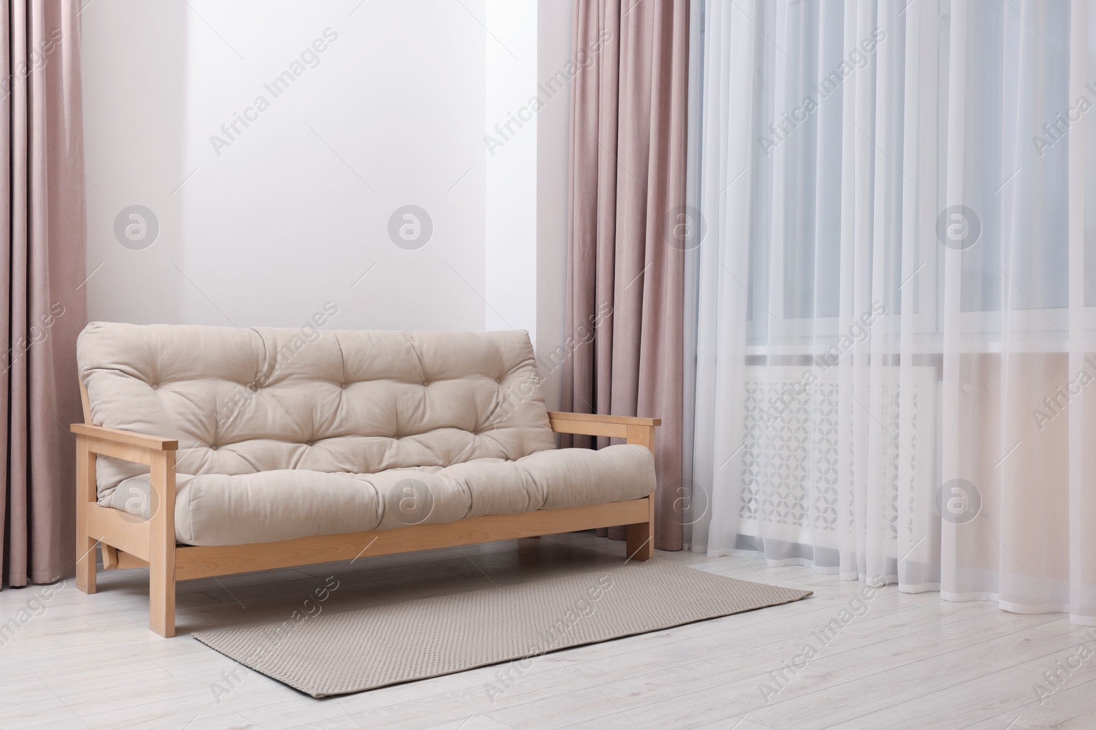 Photo of Comfortable sofa with rug in cozy light room. Interior design