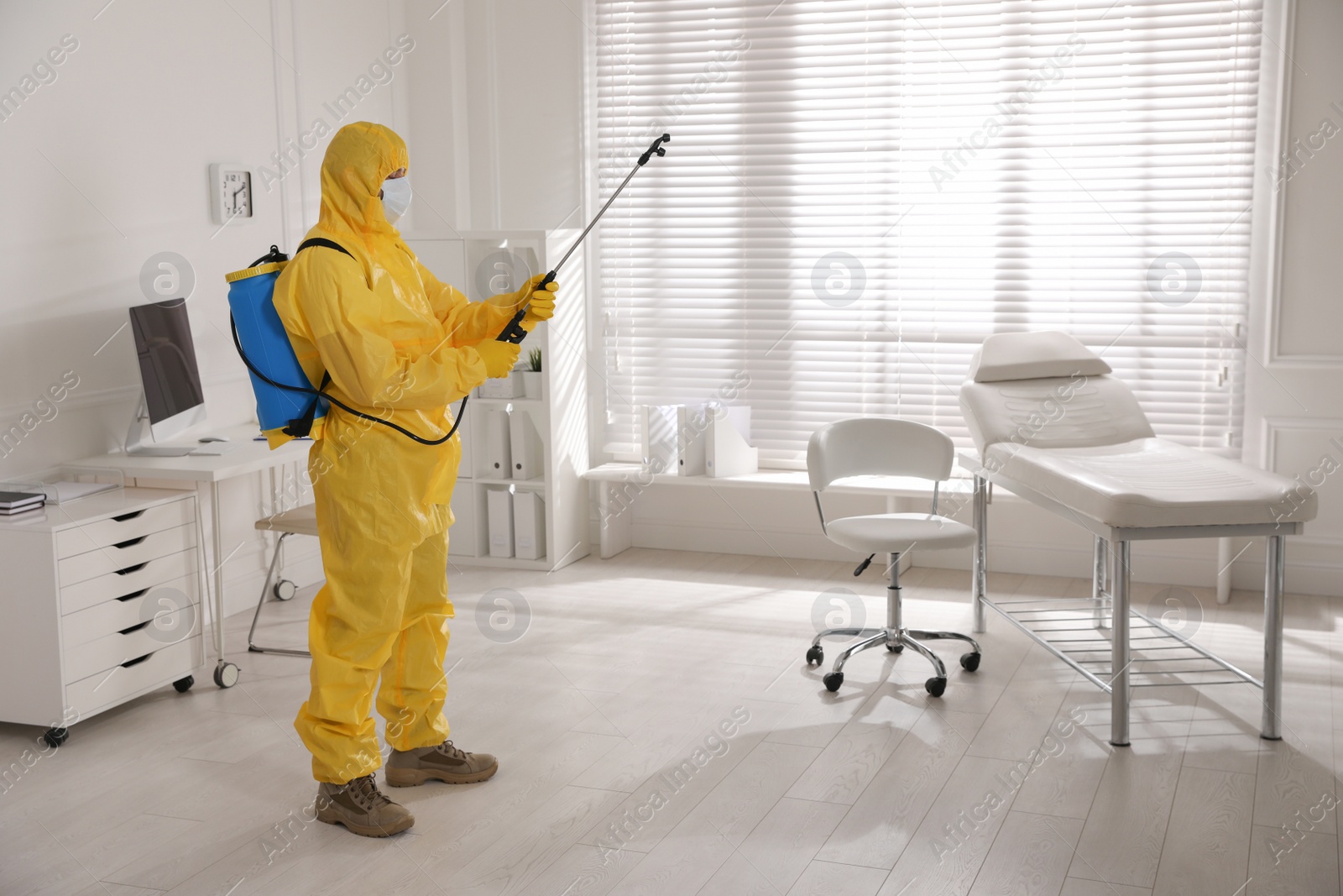 Photo of Man in protective suit sanitizing doctor's office. Medical disinfection