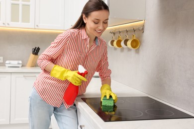 Spring cleaning. Young woman tidying up kitchen at home