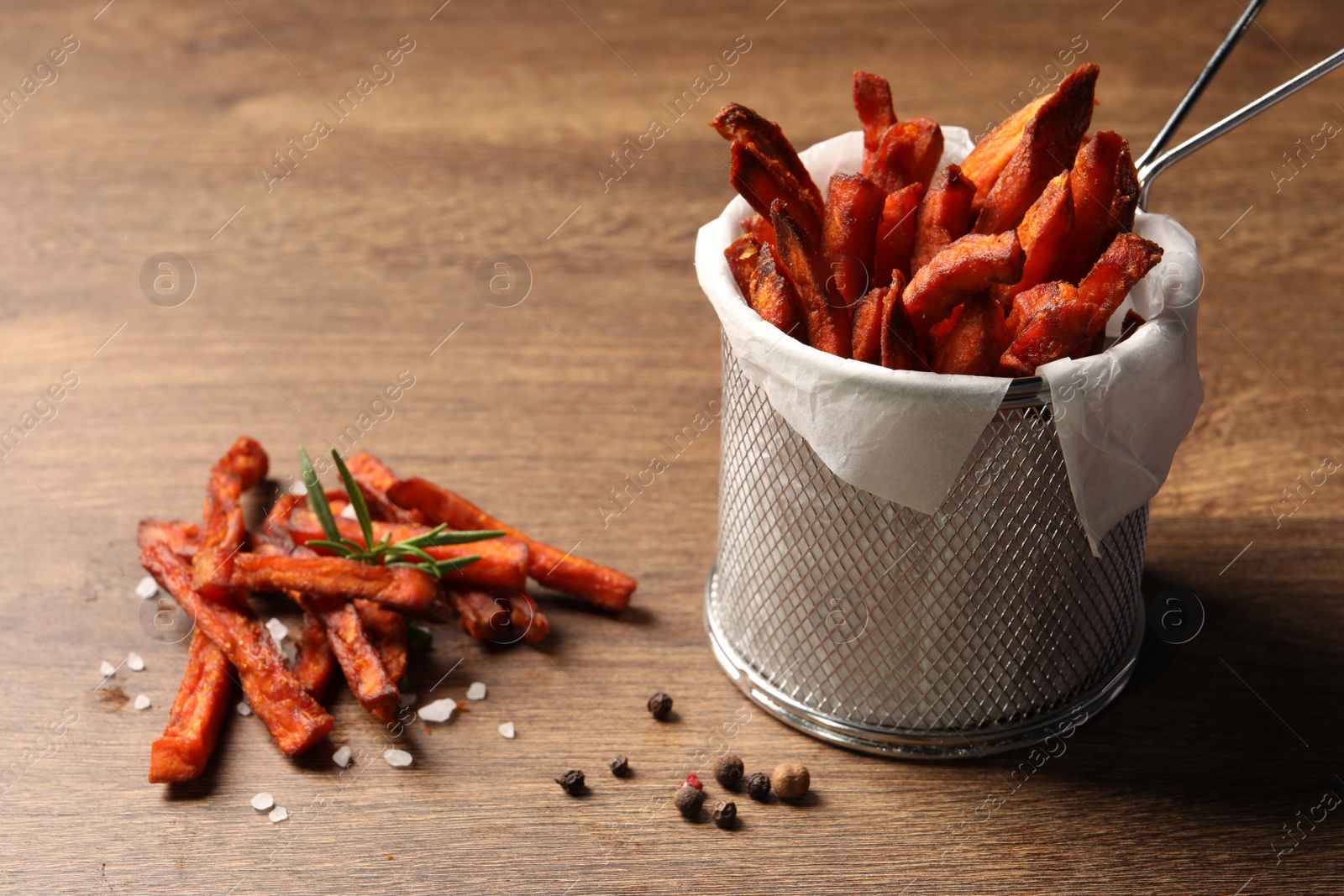 Photo of Frying basket with sweet potato fries on wooden table