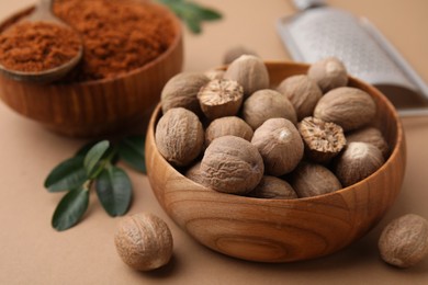 Nutmeg powder and seeds on light brown background, closeup