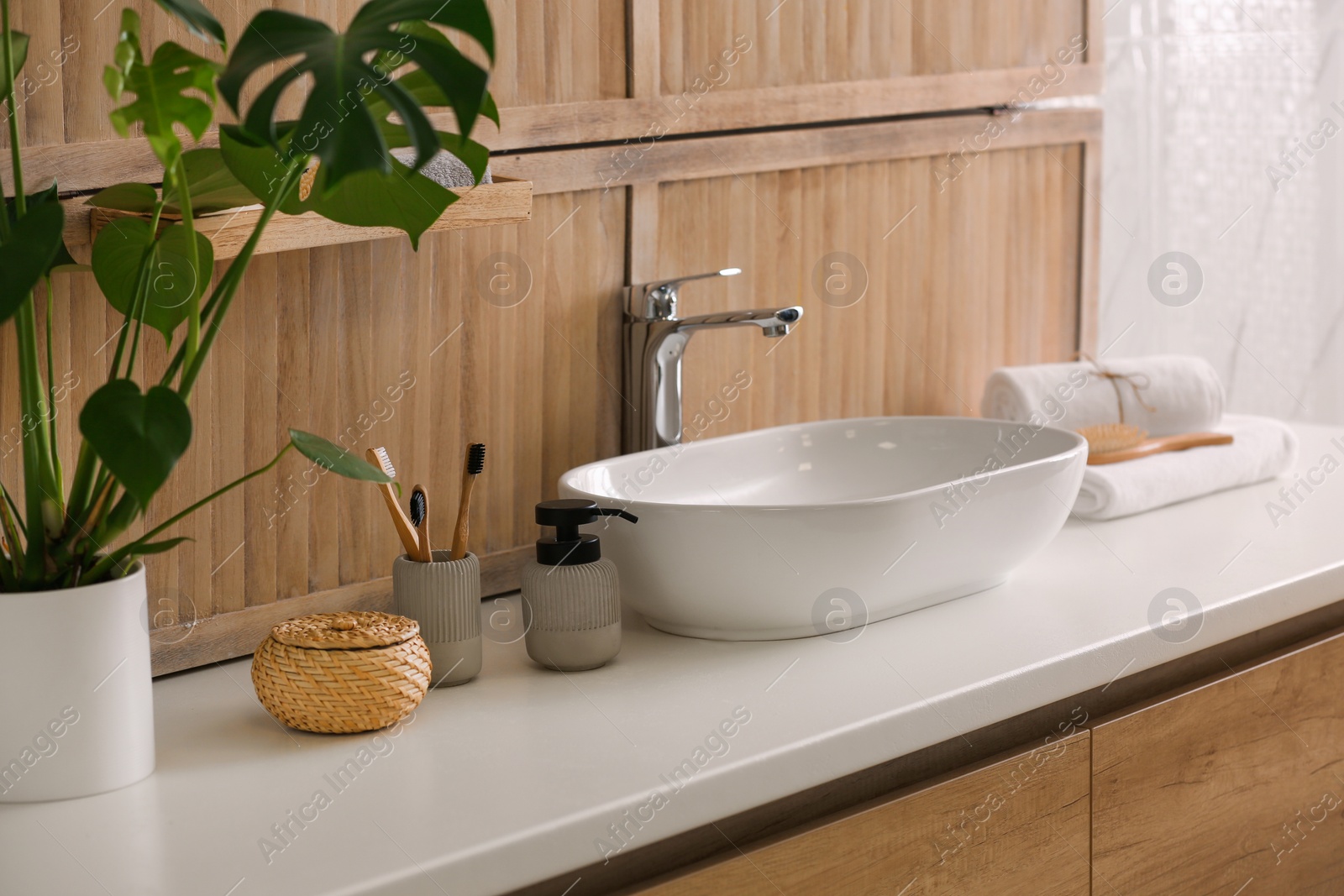 Photo of Toiletries and stylish vessel sink near wooden wall in modern bathroom