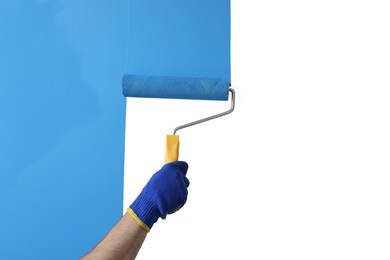 Man applying light blue paint with roller brush on white wall, closeup