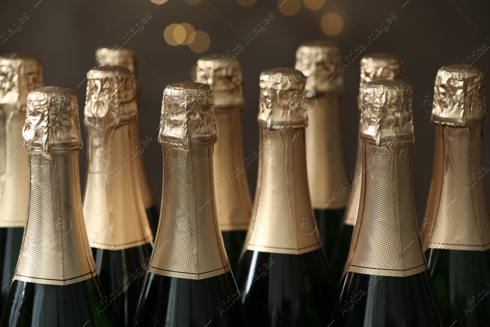 Photo of Many bottles of champagne on blurred background, closeup