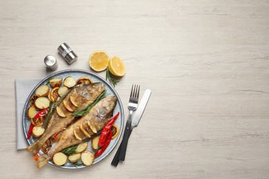 Photo of Tasty homemade roasted perches served on wooden table, flat lay and space for text. River fish