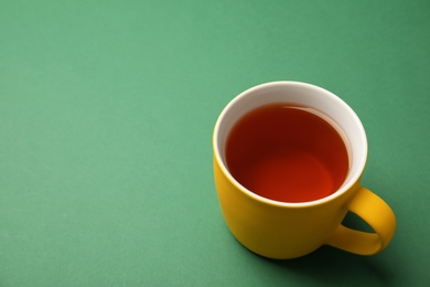 Photo of Cup of black tea on color background