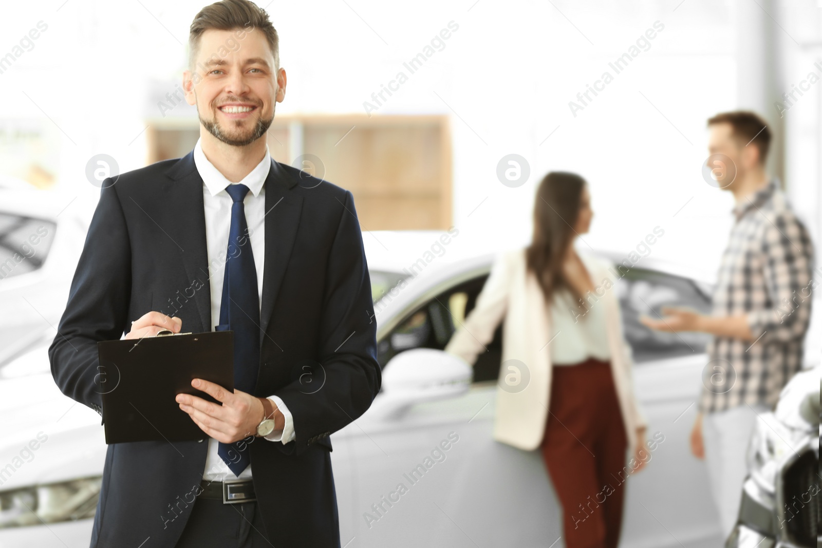 Photo of Salesman with clipboard and couple in salon. Buying new car