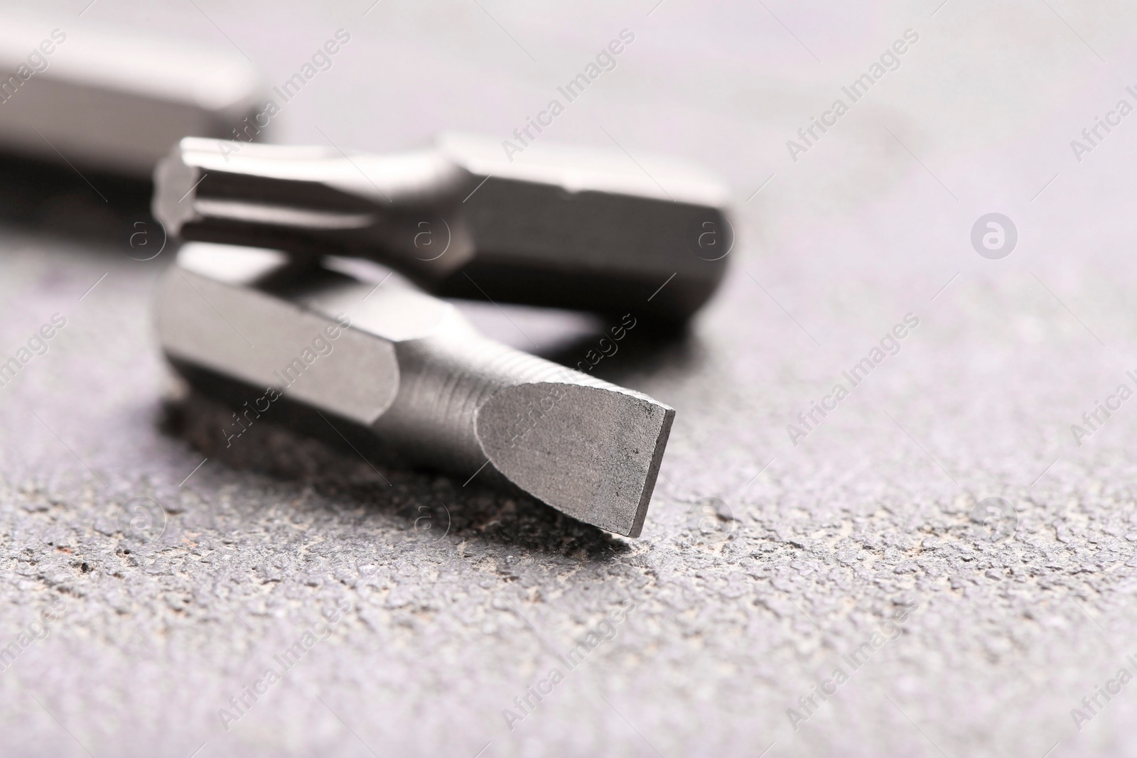 Photo of Different screwdriver bits on grey table, closeup