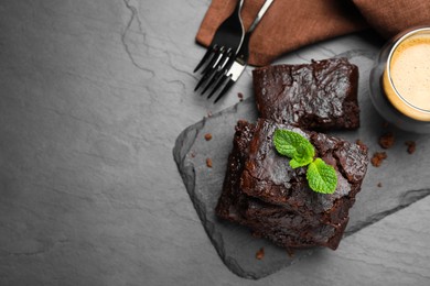 Delicious chocolate brownie with fresh mint served on black table, flat lay. Space for text