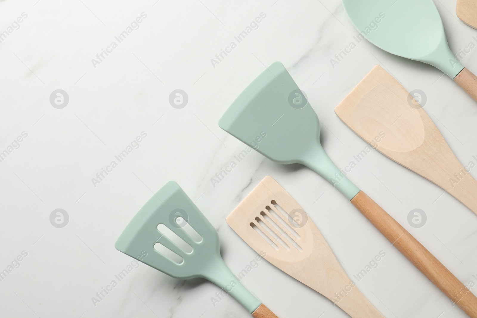 Photo of Different spatulas on white marble table, flat lay. Space for text