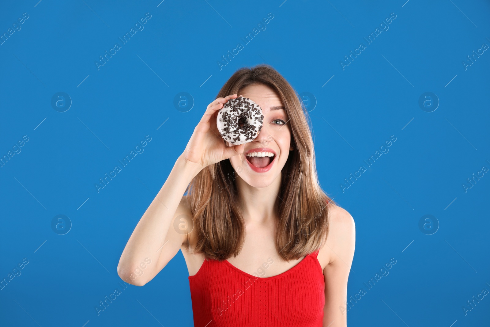 Photo of Beautiful young woman with donut on blue background