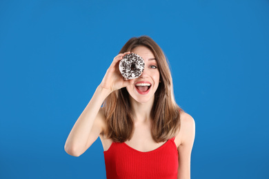 Beautiful young woman with donut on blue background