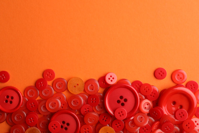 Photo of Many red sewing buttons on orange background, flat lay. Space for text