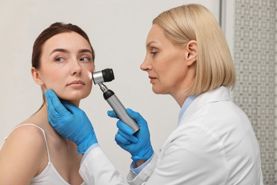 Photo of Dermatologist with dermatoscope examining patient`s face in clinic