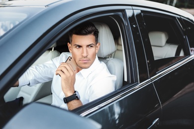 Photo of Handsome man with smartphone in modern car