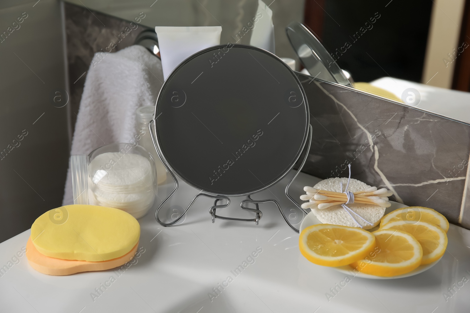 Photo of Lemon face wash. Fresh citrus fruits, personal care products and mirror on sink in bathroom