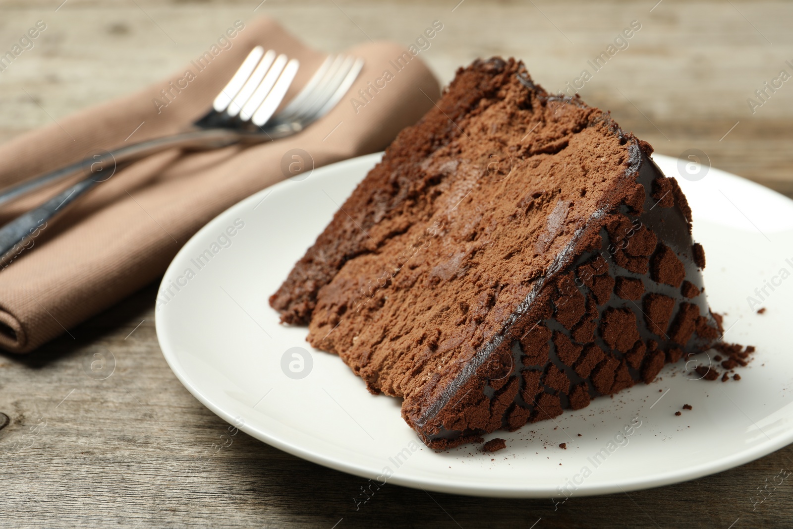 Photo of Piece of delicious chocolate truffle cake on wooden table, closeup