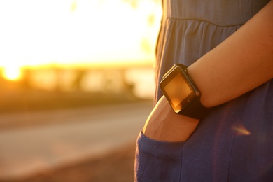 Woman with smartwatch outdoors in evening, closeup. Space for text