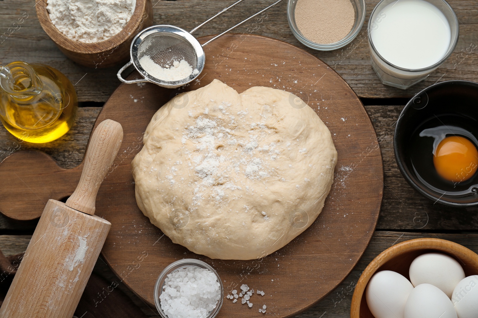 Photo of Fresh yeast dough and ingredients on wooden table, flat lay