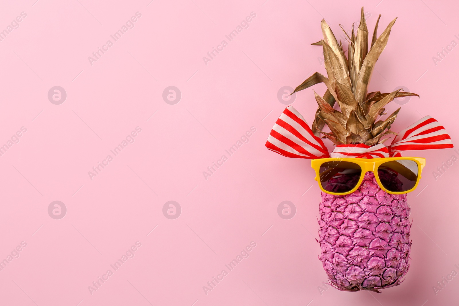 Photo of Funny pineapple with sunglasses and ribbon on color background