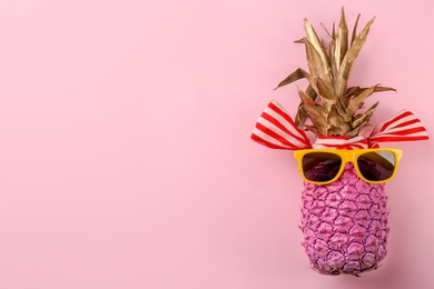 Photo of Funny pineapple with sunglasses and ribbon on color background